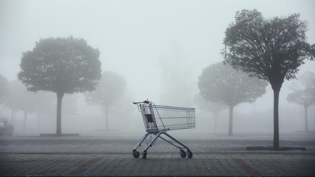 Abandoned shopping cart on parking lot in thick fog. Themes shopping, financial crisis and gloomy weather.